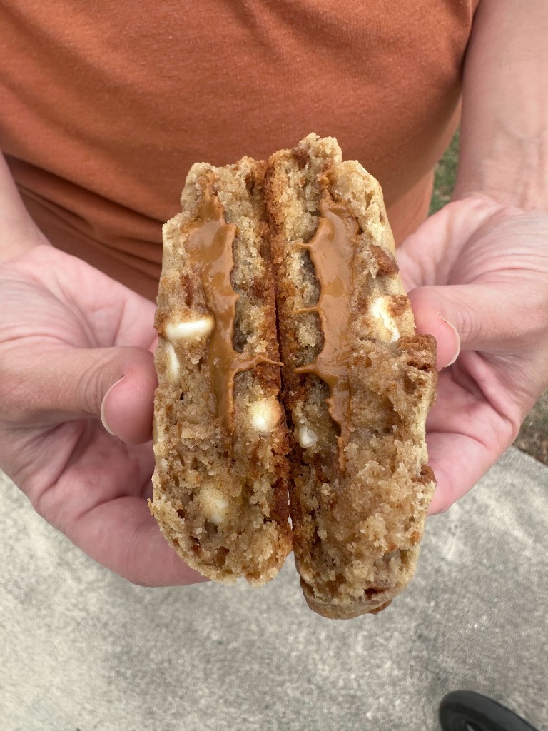 A thick sourdough cookie broken in half to show cookie butter filling and white chocolate chips